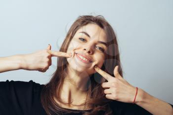 Happy cute brunette girl points a finger at the teeth