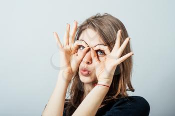 Young happy woman holding her hands over her eyes as glasses and  looking through fingers