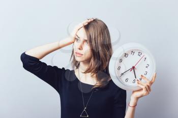 Shocked woman holding a clock