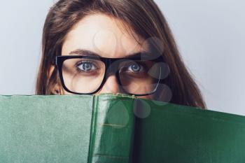 girl with glasses reading a book, looking from her