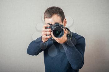 Man photographs on digital camera. On a gray background.