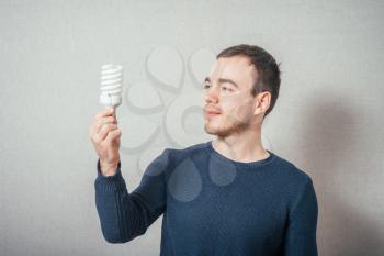 A man with a light bulb economical. On a gray background.