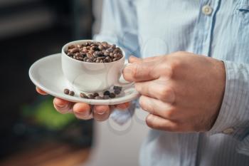 Cup of coffee beans. Young man holding a cup of coffee beans in his hands.