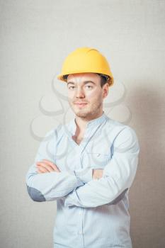 The man in yellow helmet folded his arms across his chest. On a gray background.