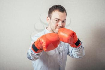 Businessman ready to fight with boxing gloves over gray background. Looking at camera