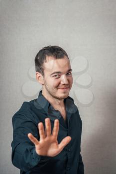 A man shows the hands stop timeout. On a gray background.