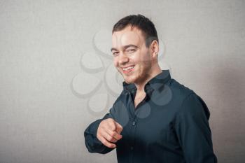 Man shows a finger forward. On a gray background.