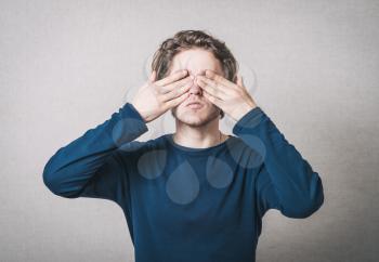 The man closed his eyes with his hands. On a gray background.