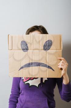 Girl with cardboard sad smiley