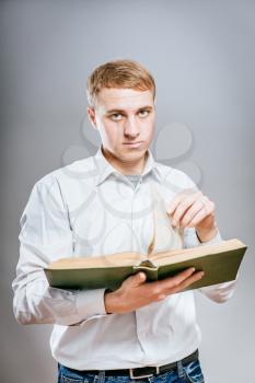 pensive young business man reding a book. on a gray background