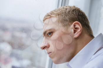 Young businessman looking out of a window and thinking