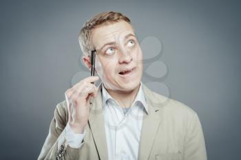 Thinking man with pen near his face isolated on gray background. Closeup portrait of a casual young pensive businessman looking up at copyspace.