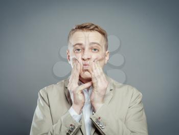 Closeup portrait of unhappy, upset, sad thoughtful young business man thinking deeply, bothered by mistakes, hands on face and cheeks, isolated on gray background. Negative, funny emotion facial expressions