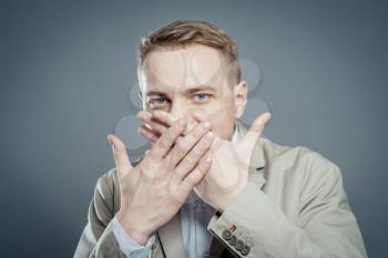 Closeup portrait of young business man closing mouth with hand, shocked, disgusted by what someone said, what he saw, isolated on white background. Negative human emotion, facial expression, feelings.