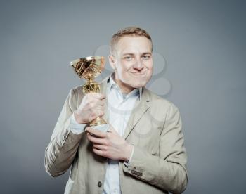 a winner with suit holding a cup/trophy over gray