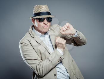 Young dancing  businessman in elegant  suit, hat and sun glasses.