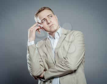 Thinking man isolated on gray background. Closeup portrait of a casual young pensive businessman looking up at copyspace. 