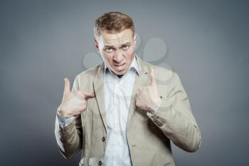 Closeup portrait of angry, mad, unhappy young guy pointing at himself as if to say, you mean me, you talking to me, Isolated on white background. Negative human emotions, facial expressions, feelings