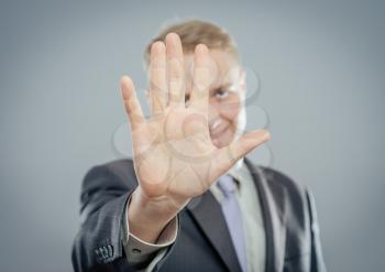 Businessman shows stop gesture, isolated on gray 
