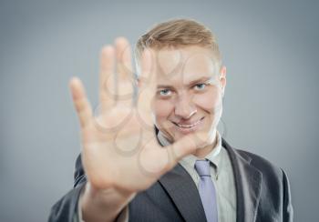Businessman shows stop gesture, isolated on gray 