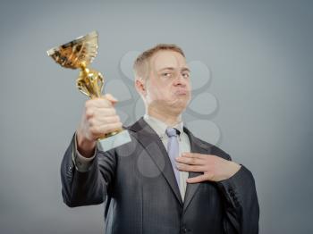 portrait of gesturing pride businessman with gold cup. Concept of win and success