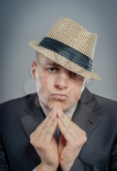 Closeup portrait desperate young man  in hat showing clasped hands, pretty please  on top isolated grey wall background. Human emotion facial expression feelings, signs symbols body language