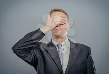 Portrait Of An Businessman Covering Eyes Isolated On Grey Background