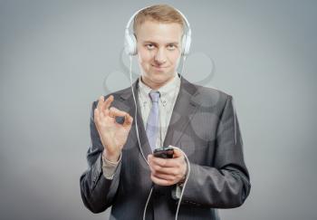 Man wearing suit listening music on phone and show ok