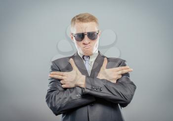 Handsome young man in sunglasses crossed his arms in the form of pistols. Gesture. Isolated yellow background. photo
