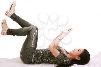 beautiful young girl laying on a pillow chatting on a cell phone 
