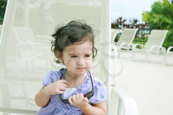 cute toddler girl in summer clothes and sunglasses lyiing on a lounge and relaxing in tropic ocean background 