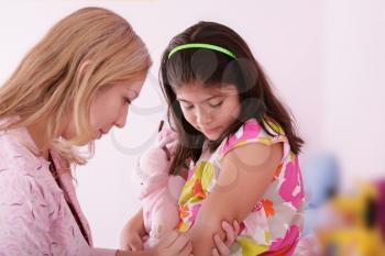 Doctor give injection to girl's arm, focus on the little girl.
