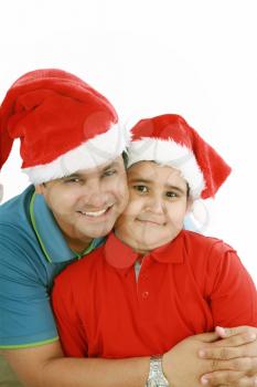 Happy father and son with Christmas hats look to the camera