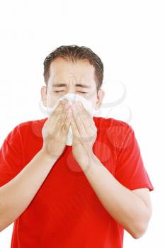 Young man with a cold blowing nose on tissue 
