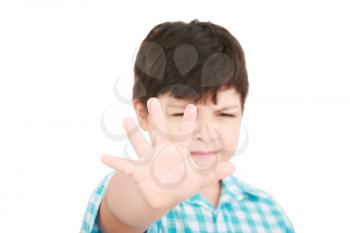 Child looking at camera. Stop signal with his hand.  Boy trying to defend himself isolated on white 