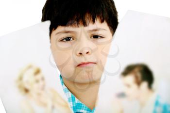 Upset boy standing in front pcture of parents with problems against white background 