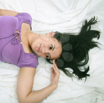 close-up portrait of beautiful female face with long black hairs laying down on the bed