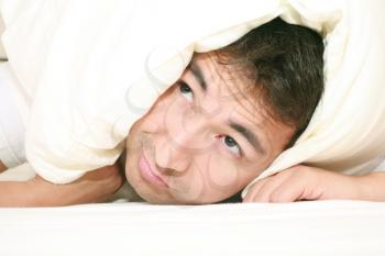 Man trying to sleep with a pillow over his head and close to wake up time

