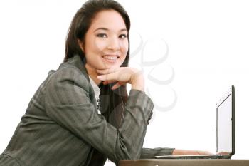 Laptop woman smiling looking at camera. Young happy businesswoman sitting at table with computer. Asian / Caucasian model. 