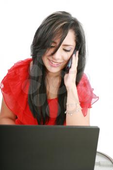 Portrait of a smiling young business woman speaking on mobile phone while using laptop in office 
