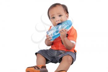 Adorable one year old child biting bottle and smiling, isolated on white. 