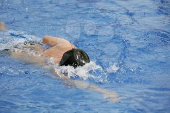 Young man swimming the front crawl in a pool 