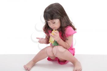 Close-up of beautiful little girl drinking from a juice box. Shot in studio over white. 