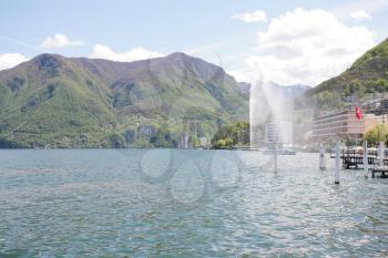 Mountainside villas and appartments at lake with waterfountain in the city of Lugano in Switzerland 
