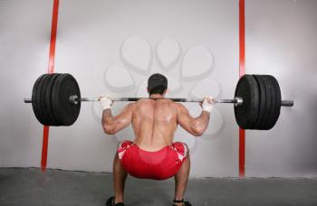 The concept of power and determination of a man lifting a weight bar.  Back squat crossfit exercise.  Focus on the back.