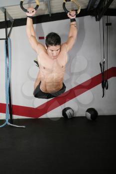 Ring dip crossfit exercise over a dark background.
