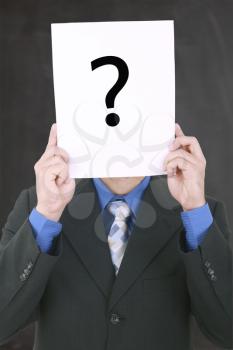 Young businessman holding a white billboard with a question mark on it 

