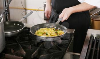 Chef cooking rigatoni with vegetables in a pan