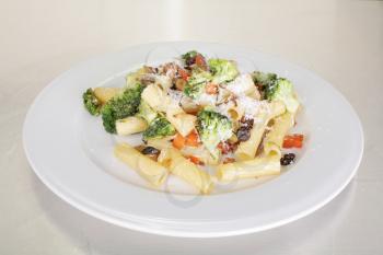 Rigatoni with vegetables served on a white plate. 