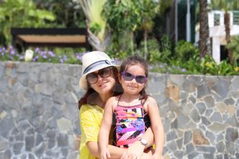 Mother and daughter enjoying the summer outdoors with fancy sunglasses.  Focus in the little girl.